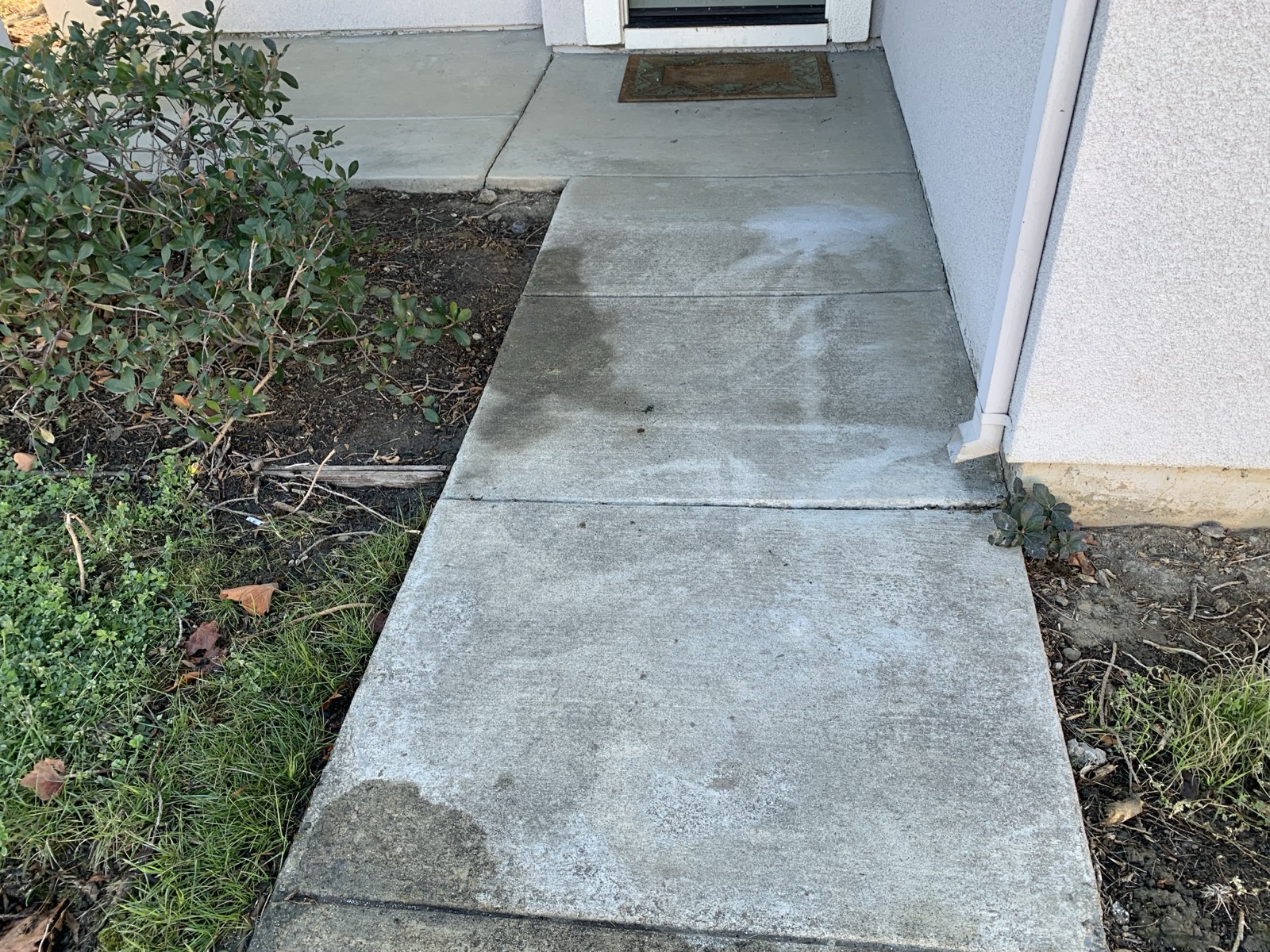 Before — entry walkway to the front door of the Fremont home with patchy dark grime and staining