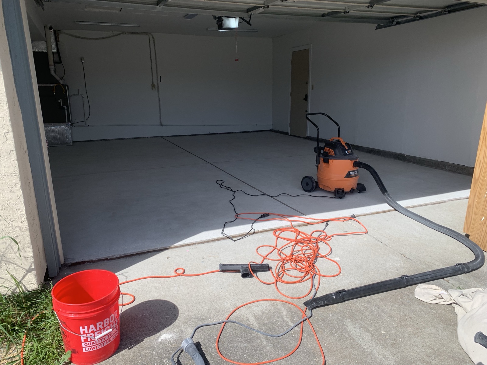 Before — bare Fremont garage concrete slab during prep, shop vac and cords staged before epoxy coating