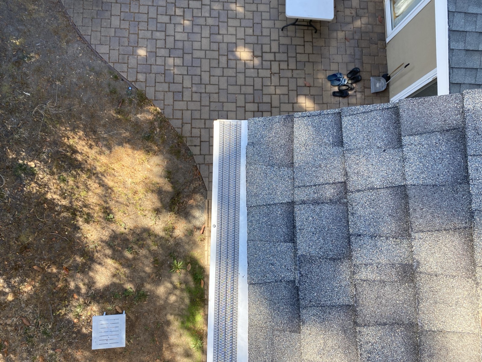 Micro-mesh gutter guard seen from above the roof edge — mesh panel sealed over a clean gutter run