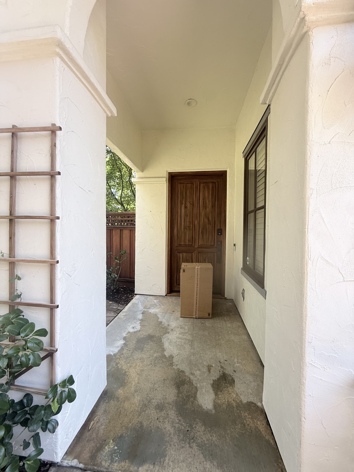 After — covered entry of the Los Gatos home with clean stucco columns and wood front door, concrete still drying