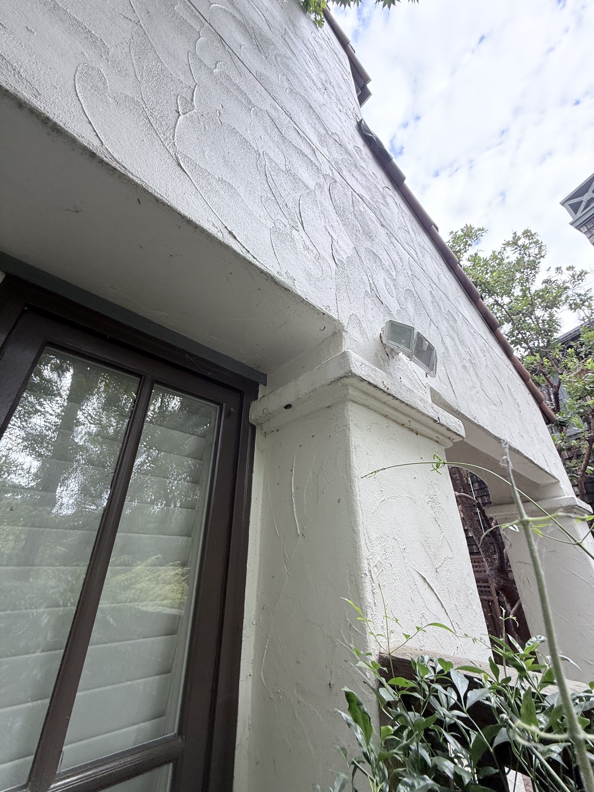 Before — textured stucco wall and porch header on the Los Gatos home with cobwebs and dirt specks around the floodlight