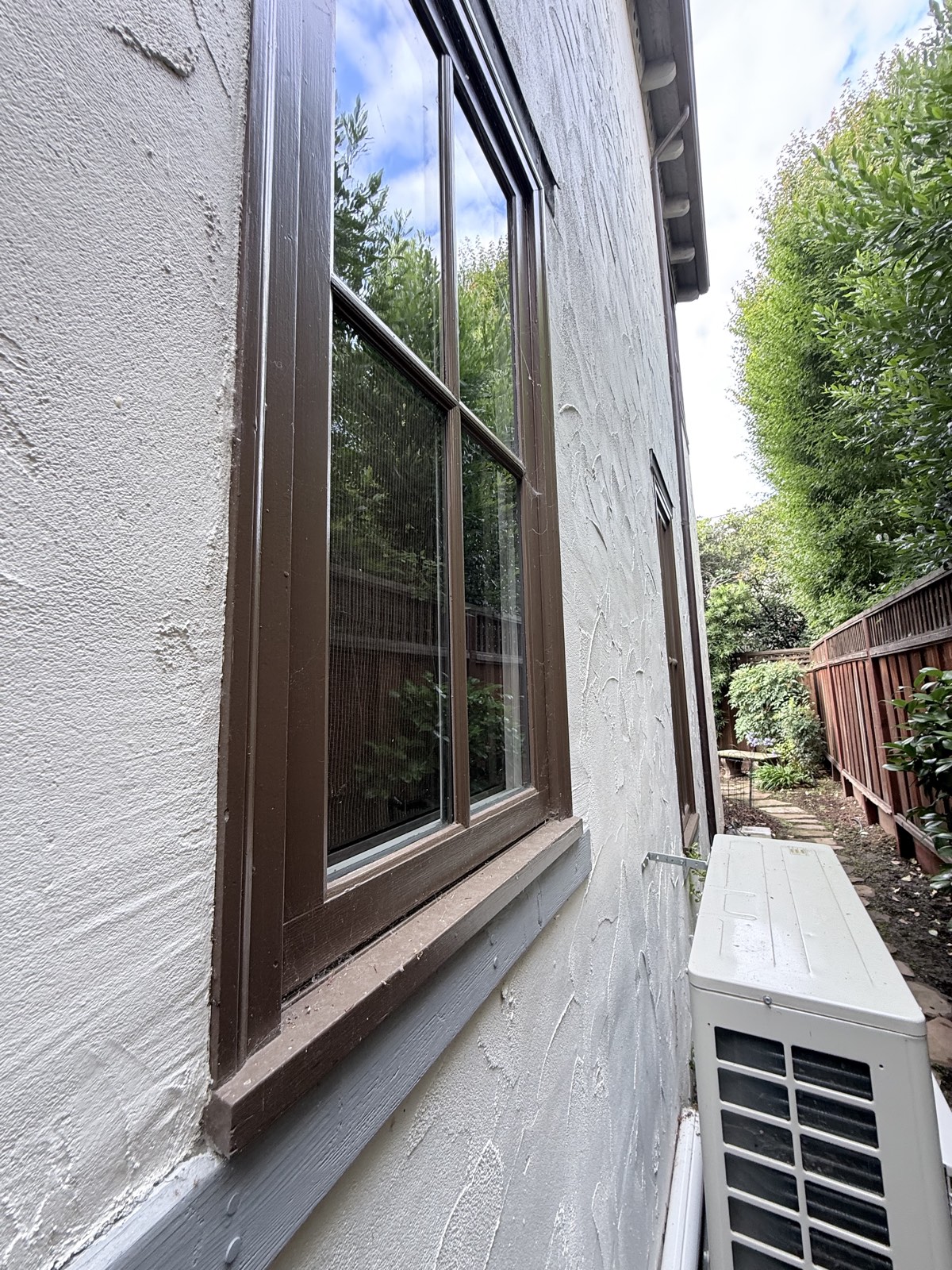 Before — side-yard window of the Los Gatos home with dusty frame and cobwebs above the mini-split unit