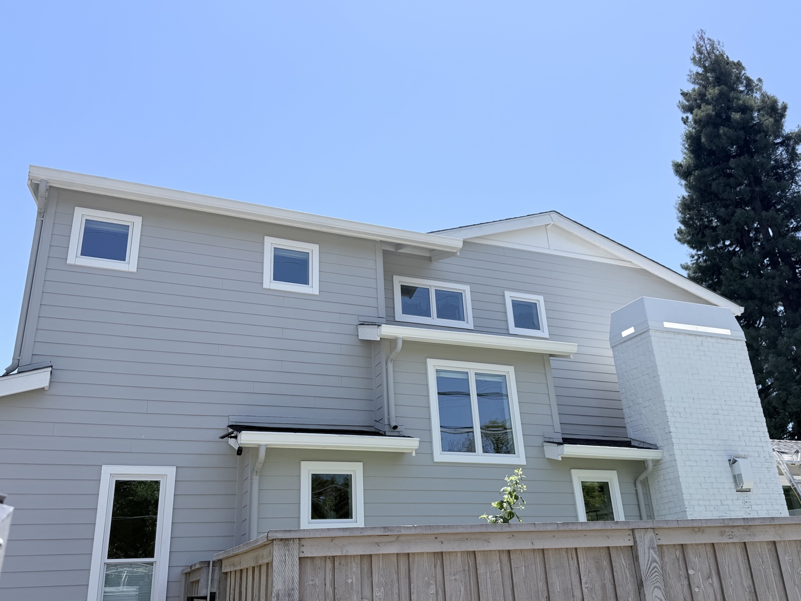 After — rear elevation of the two-story Menlo Park home clean, gray lap siding and white trim uniform again