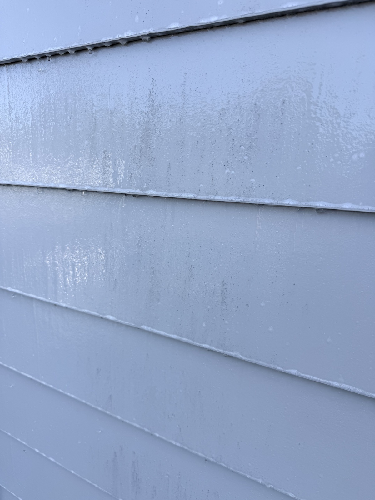 Before — dirt streaks and grime film on light gray lap siding of a Menlo Park home, wet with cleaning solution