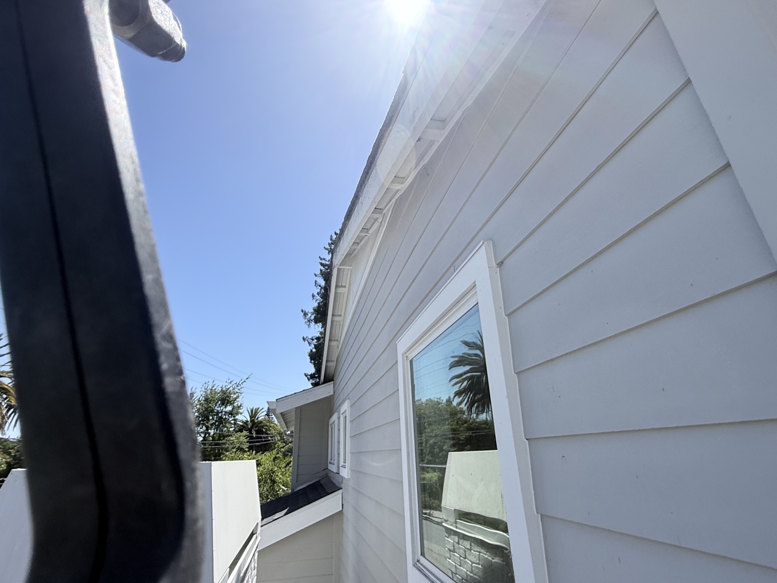 Before — wash pole reaching upper-story siding of a Menlo Park home, dust film still on the boards
