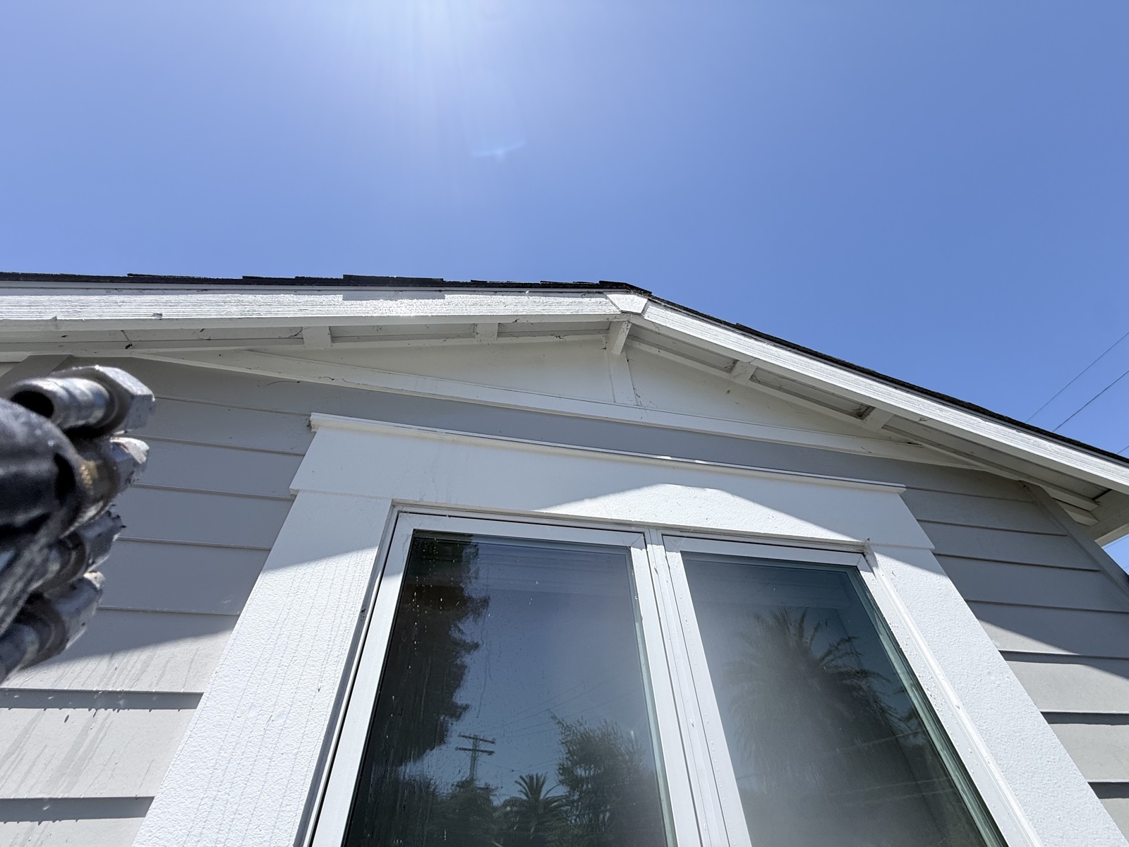 Before — soft washing under way at the gable end of a Menlo Park home, siding above the window still dull