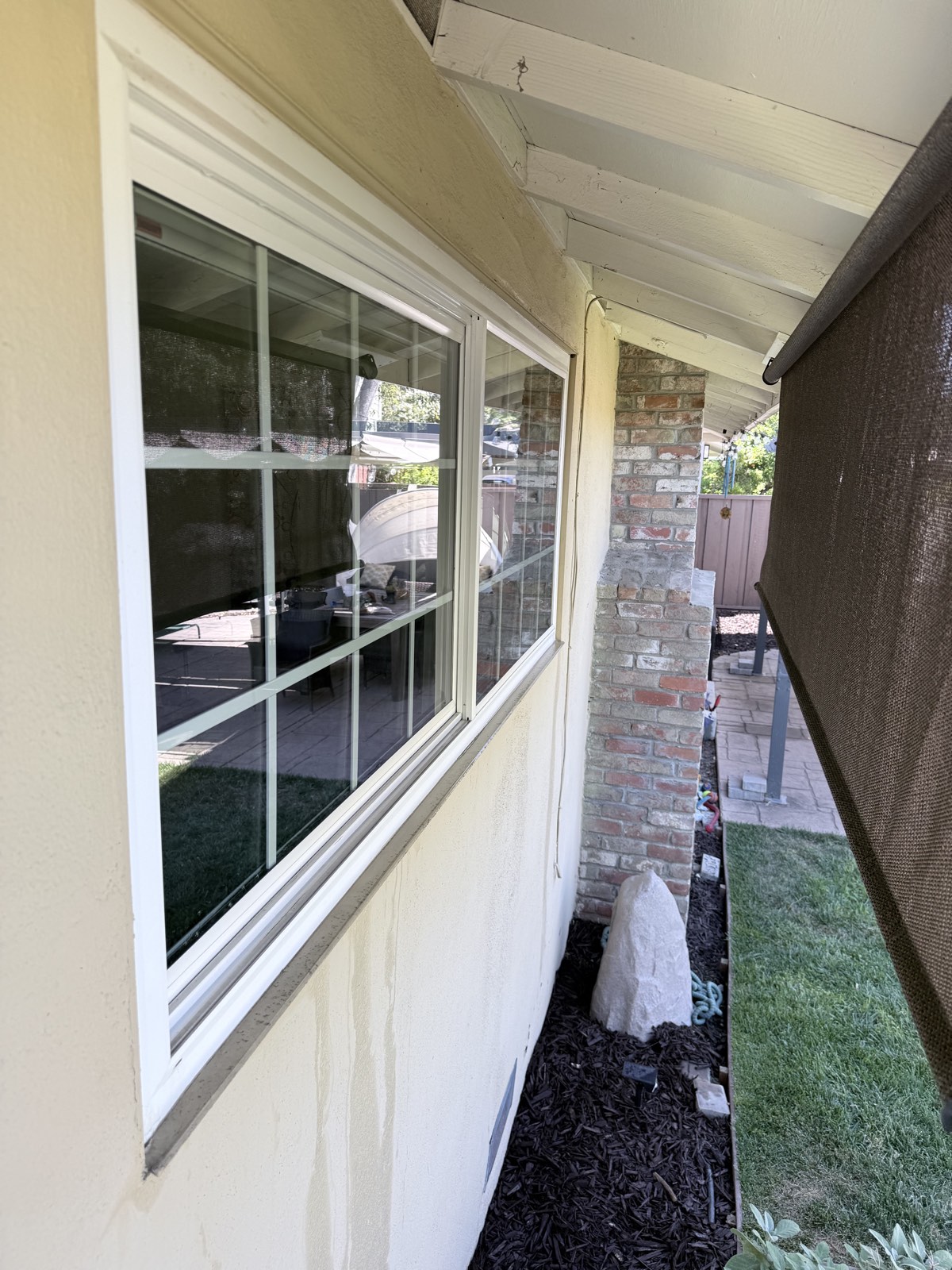 After — spot-free grid window reflecting the backyard patio and brick chimney